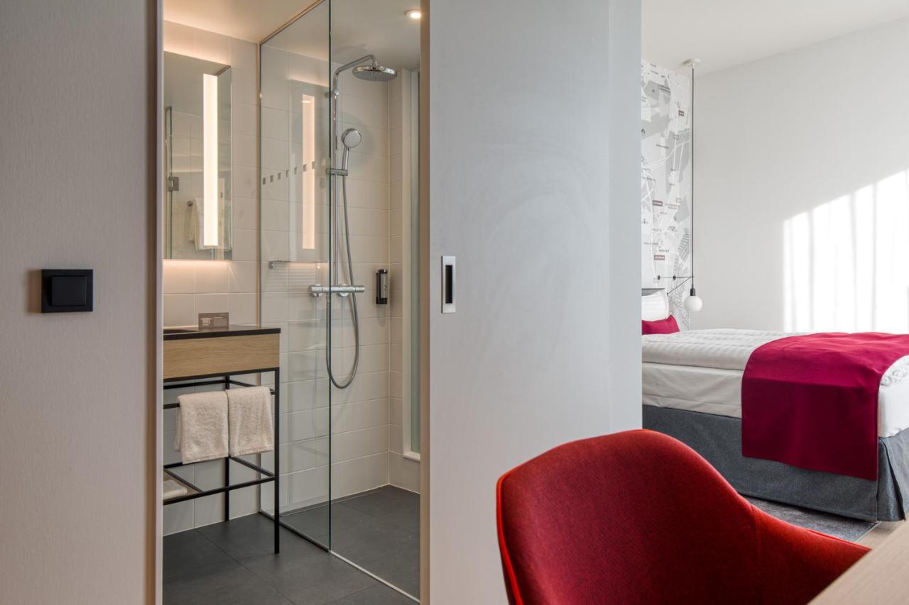 Intercityhotel Berlin Airport Ber Terminal 1 & 2 舍讷费尔德 外观 照片 The photo shows a modern hotel room or bathroom space. On the left, there is a glass-enclosed shower area with a sleek design, featuring a showerhead and minimalist fixtures. Adjacent to the shower, there's a sink area with a stylish countertop and a